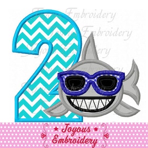 May include: Embroidered design of a blue number two with a white chevron pattern and a gray shark wearing blue sunglasses. The text "Joyous Embroidery" is below the design.