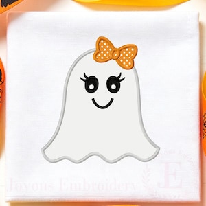 May include: A white fabric square featuring an embroidered ghost design. The ghost is white with black eyes, long eyelashes, and a smiling mouth. An orange bow with white polka dots is positioned on the top of the ghost's head. The text Joyous Embroidery is visible.