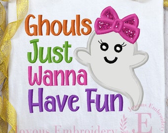 May include: White t-shirt featuring the text "Ghouls Just Wanna Have Fun" in orange, green, pink, and purple. A smiling ghost with a pink glitter bow is on the right. A Halloween-themed design.