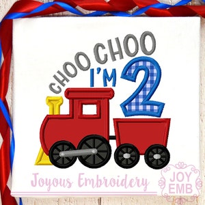 May include: Embroidered design of a red toy train with a blue and white checkered number 2 on top. The text "Choo Choo I'm 2" is above the train. The text "Joyous Embroidery" is below the train.