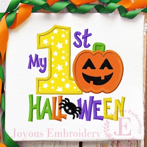 May include: White fabric with the text "My 1st Halloween" in purple, green, orange, and yellow. A yellow number 1 is filled with white stars. An orange jack-o'-lantern and a black spider are also featured.
