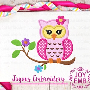 Pode incluir: Coruja rosa e branca de bolinhas com uma flor na cabeça, sentada em um galho com folhas verdes e flores azuis. A coruja tem olhos amarelos e um bico marrom. O texto "Joyous Embroidery" está abaixo da coruja.
