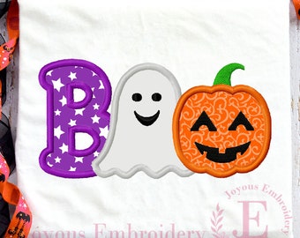 May include: White t-shirt with a purple "B" filled with white stars, a smiling white ghost, and an orange jack-o'-lantern with a green stem. The design is embroidered. The shirt is decorated with Halloween-themed ribbon.