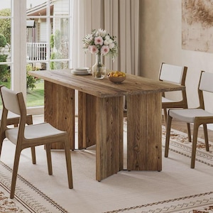 Puede incluir: Una mesa de comedor rectangular de madera con acabado de veta natural y dos patas de soporte verticales anchas y planas. La mesa está rodeada por cuatro sillas con marcos de madera y asientos tapizados de color claro, con un florero de cristal.