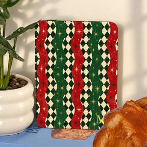 May include: A rectangular board featuring a repeating pattern of vertical wavy red and green stripes interspersed with cream-coloured diamond shapes. The design includes small gold starburst accents throughout and a gold letter M in the corner.