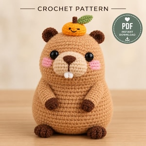 Peut inclure: Un modèle de crochet PDF en téléchargement instantané représentant un capybara amigurumi beige avec un petit fruit orange sur la tête. Le capybara a des yeux noirs, des joues roses, un nez marron et deux dents blanches. Texte : CROCHET PATTERN et PDF.