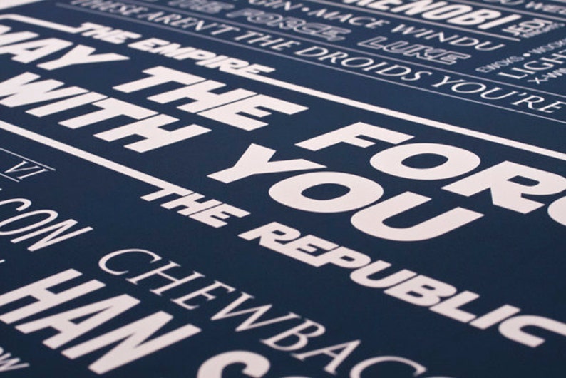 May include: A navy blue poster with white text that reads "May the Force be with you" and "The Republic". The poster also includes the names of characters from the Star Wars franchise, including "Luke", "Han", "Chewbacca", and "Obi-Wan Kenobi".