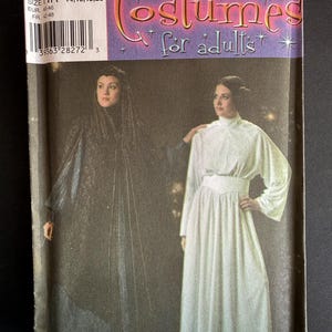 Puede incluir: Un sobre de patrón de costura Simplicity 4443 para disfraces de adultos. El frente muestra dos atuendos: un vestido oscuro texturizado con un tocado y un vestido blanco de manga larga con cuello alto y cintura ancha. El texto dice Costumes for adults.
