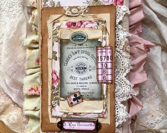 May include: A handmade journal with a layered cover featuring floral paper, vintage-style ephemera, and lace trim. The cover displays the text 789, Clark's O.N.T. Spool Cotton, 15780, 10, 8, 6, and 3. Rue Pirouette, with a playing card suit icon.
