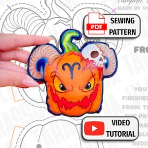 May include: An orange pumpkin-shaped leather craft piece featuring a ram's horns, a skull, and the Aries zodiac symbol. The design includes a green stem and a jagged red mouth. Text labels include PDF SEWING PATTERN and VIDEO TUTORIAL.