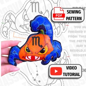 May include: A plush toy shaped like a pumpkin with a scorpion tail and claws, featuring an orange body, blue limbs, and a black Scorpio zodiac symbol. The text PDF SEWING PATTERN and VIDEO TUTORIAL are displayed in white boxes.