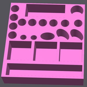 May include: A bright pink rectangular organiser tray featuring a variety of recessed compartments. The layout includes multiple circular holes of different sizes, three large square sections, one long rectangular slot, and several oval-shaped cutouts.