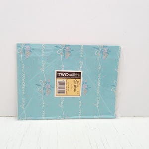 Könnte beinhalten: Eine Packung Geschenkpapier mit hellblauem Hintergrund. Das Papier hat ein sich wiederholendes Muster aus Blumensträußen und die Worte "on Mother's Day" in Schreibschrift. Die Verpackung ist mit "TWO SHEETS Gift Wrap" beschriftet.