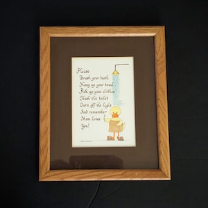 May include: A framed print with a yellow duck illustration and the text "Please: Brush your teeth Hang up your towel Pick up your clothes Flush the toilet Turn off the light And remember Mom loves You!"