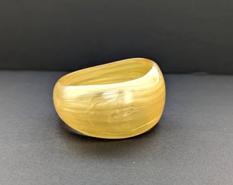 May include: A gold-coloured plastic bangle bracelet with a swirl pattern.