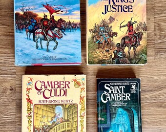 May include: Four vintage paperback books by Katherine Kurtz. Titles include "The Bishop's Heir," "The King's Justice," "Camber of Culdi," and "Saint Camber." The covers feature illustrations of medieval scenes with knights, castles, and fantasy elements.