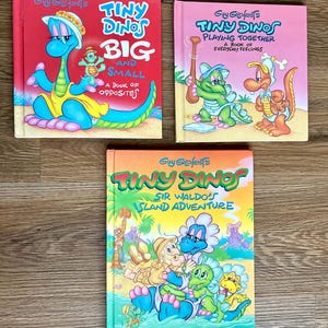 May include: Three children's books with dinosaur illustrations. The books are titled "Tiny Dinos Big and Small", "Tiny Dinos Playing Together", and "Tiny Dinos Sir Waldo's Island Adventure". The books have colorful covers with cartoon dinosaurs.