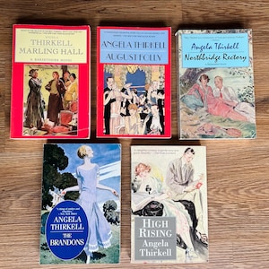 May include: Five paperback books by Angela Thirkell, all with similar cover designs featuring illustrations of people in vintage clothing. The titles are "Marling Hall", "August Folly", "Northbridge Rectory", "The Brandons", and "High Rising".