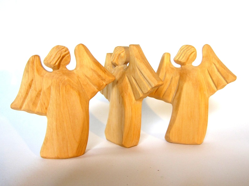 May include: Three wooden angel figurines with outstretched wings. The angels are carved from light brown wood and have a simple, rustic design.