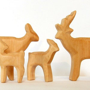 May include: A set of four wooden deer figurines, including a buck with antlers, a doe, and two fawns. The figurines are all carved from light-colored wood and have a natural finish.