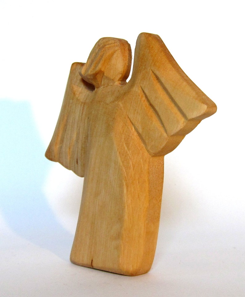 May include: A wooden angel figurine with outstretched wings. The angel is carved from light brown wood and has a simple, elegant design.