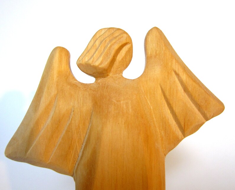 May include: A wooden angel figurine with outstretched wings. The angel is carved from light brown wood and has a simple, elegant design.