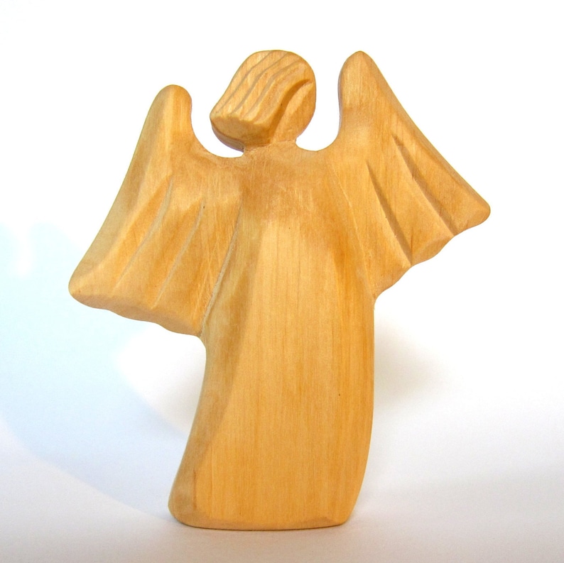 May include: A wooden angel figurine with outstretched wings. The angel is carved from light brown wood and has a simple, stylized design.