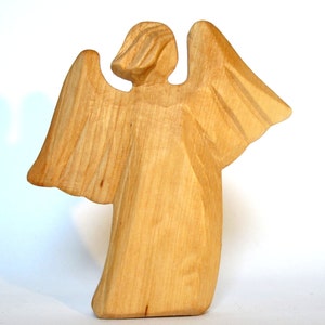 May include: A wooden angel figurine with outstretched wings. The angel is carved from light brown wood and has a simple, stylized design.