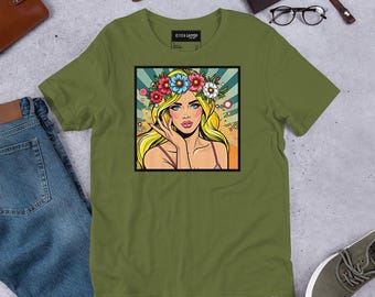 Può includere: Una maglietta verde con un'illustrazione pop art di una donna con i capelli biondi che indossa una corona di fiori. La donna guarda di lato e ha la mano sul mento.