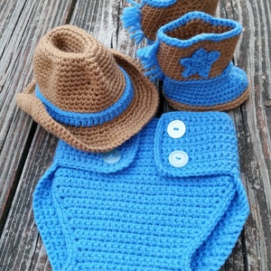 Può includere: Un completo da cowboy in crochet per neonati in marrone e blu. Il completo comprende un cappello, un copri pannolino e stivaletti.