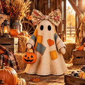 May include: A cream-colored fabric ghost figurine featuring a large floral print bow on its head and various colorful patches sewn onto its body. The ghost holds a small orange plastic jack-o'-lantern bucket with a black handle in its hand.