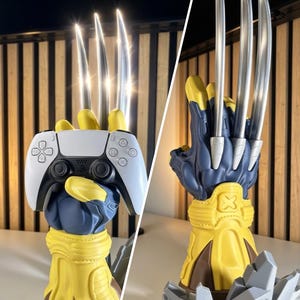 Peut inclure: Un support de manette en forme de gantelet bleu et jaune avec trois longues griffes argentées métalliques dépassant des articulations. Le support maintient une manette de jeu sans fil blanche et noire. La base présente des formes rocheuses grises.