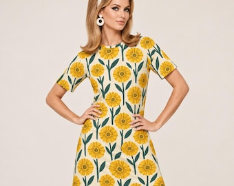 May include: A short-sleeved mini dress featuring a cream-coloured base with a repeating pattern of yellow sunflowers and dark green stems. The dress has a round neckline and a straight-cut silhouette that falls above the knee.