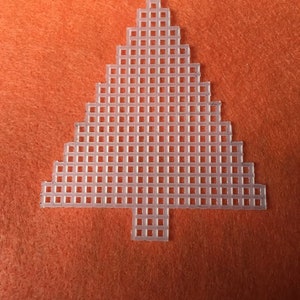 May include: A clear plastic Christmas tree shape with a grid pattern, set against an orange background. The tree is made of small, connected squares, creating a pixelated effect. Ideal for crafting or holiday decorations.