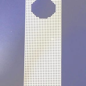 May include: A white plastic door hanger with a grid pattern of small square holes. The top portion features a large, circular cutout. The background is a solid, muted blue.