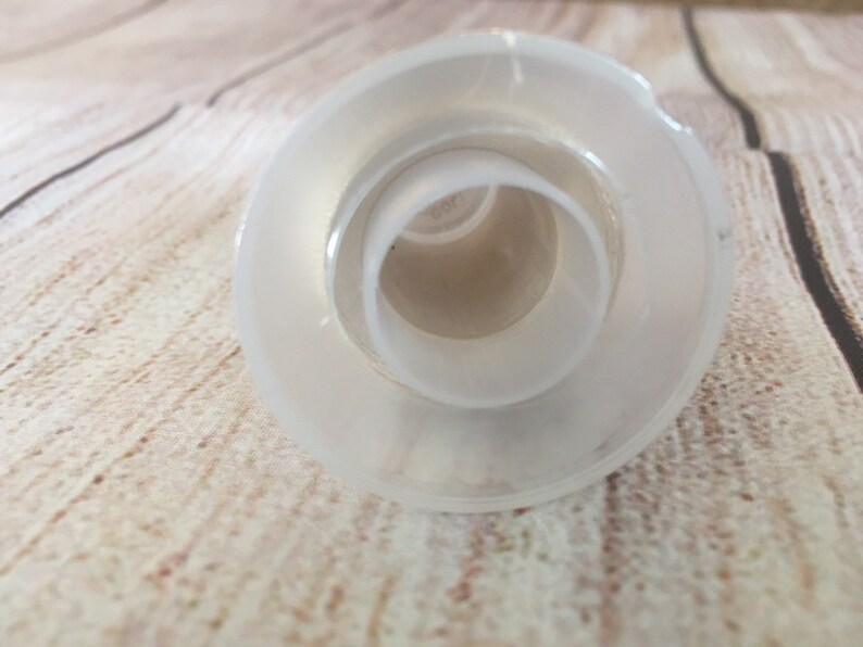 K&ouml;nnte beinhalten: Ein klarer, mattierter Glasflaschenverschluss mit kreisf&ouml;rmigem Design. Der Verschluss hat eine breite, flache Basis und eine Reihe konzentrischer Ringe, die sich zur Mitte hin verj&uuml;ngen. Das Objekt besteht aus Glas und ist f&uuml;r die &Ouml;ffnung einer Flasche bestimmt.