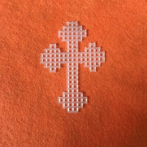 Op de afbeelding: Een doorzichtig plastic kruis met een rasterpatroon, tegen een oranje achtergrond. Het kruis heeft een traditionele vorm met een verticale steel en vier armen, elk met een uitlopend uiteinde. Het ontwerp is eenvoudig en geometrisch.