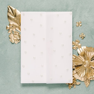 May include: A white card with a pearl pattern on a light green background. The card is surrounded by gold metallic flowers.