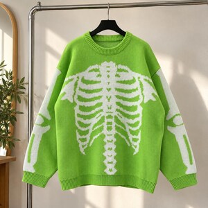 May include: A lime green long-sleeve knit sweater featuring a prominent white graphic of a human rib cage and spine on the front, with matching white arm bone patterns extending down the sleeves and a ribbed crew neckline.