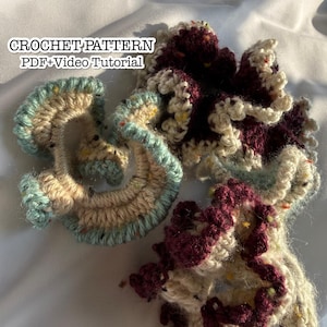 Puede incluir: Tres coleteros de ganchillo con bordes de volantes, hechos de hilo color crema, azul claro y burdeos oscuro con motas de colores. El texto CROCHET PATTERN PDF+Video Tutorial es visible en la esquina superior izquierda.