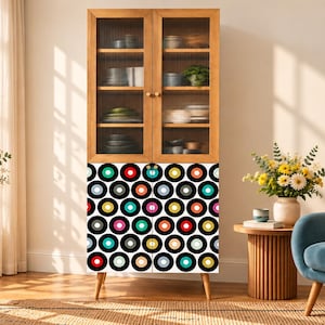 Op de afbeelding: Een hoge houten kast met twee glazen deuren aan de bovenkant met verticale ribbels en twee dichte deuren aan de onderkant, versierd met een herhalend patroon van kleurrijke cirkels in rood, blauw, groen, geel en roze op een zwarte achtergrond.
