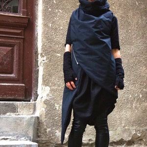May include: A black asymmetrical top with a high neck and long sleeves. The top is worn with black leggings and black lace-up boots.
