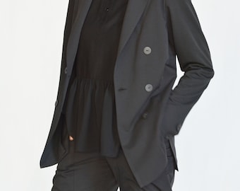 May include: A black double-breasted blazer with a black top underneath. The blazer has two buttons and a long sleeve.