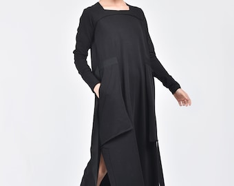 May include: A black long-sleeved maxi dress with a square neckline and a single large pocket on the left side. The dress has a unique asymmetrical design with a slit on the left side and a long, flowing skirt.