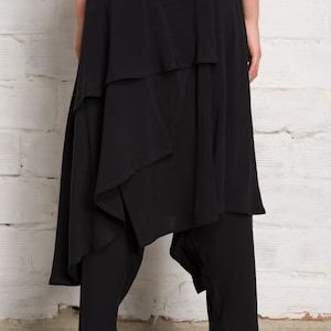 Pode incluir: Saia preta em camadas com um design assim&eacute;trico &uacute;nico. A saia tem uma cintura larga e chega aos tornozelos. A saia &eacute; feita de um tecido leve e &eacute; perfeita para um look casual ou elegante.