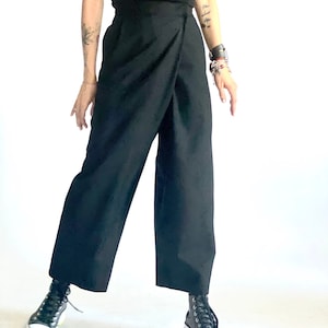 May include: A person wearing black wrap pants with a high waist and black high-top sneakers.