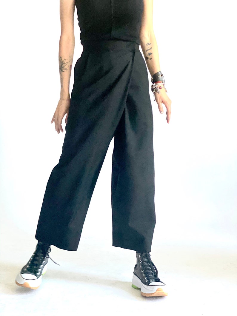May include: A person wearing black wrap pants with a high waist and black high-top sneakers.