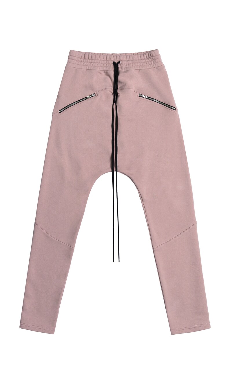 Peut inclure: Un pantalon de surv&ecirc;tement rose clair avec une taille &agrave; cordon et des poches zipp&eacute;es. Le pantalon de surv&ecirc;tement a une coupe d&eacute;contract&eacute;e et une jambe l&eacute;g&egrave;rement fusel&eacute;e.