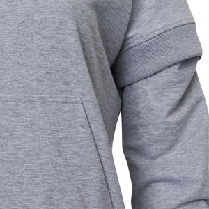 May include: A gray long-sleeved sweatshirt with a raglan sleeve design and a kangaroo pocket. The sweatshirt has a ribbed cuff and hem.