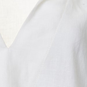 May include: Close-up of a white v-neck shirt with a stitched seam detail.